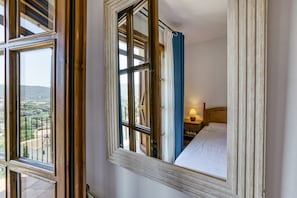 Un dormitori amb una finestra gran, un llit i una nit abill amb una làmpada.