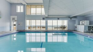 Une grande piscine intérieure offrant une vue dégagée sur l’océan grâce à de larges baies vitrées.