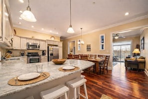 Una cocina amplia con una isla grande, electrodomésticos modernos y un comedor con mobiliario de madera.