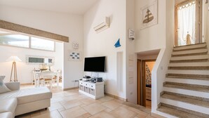 Een woonkamer met een bank, televisie en een trap.