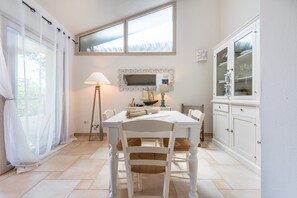 A dining area with a white table, chairs, a lamp, a mirror, and a cabinet.