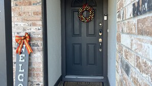 A dark grey door with a wreath and a 'WELCOME' sign.