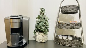 A coffee maker, a potted plant, and a wicker basket with items on a table.