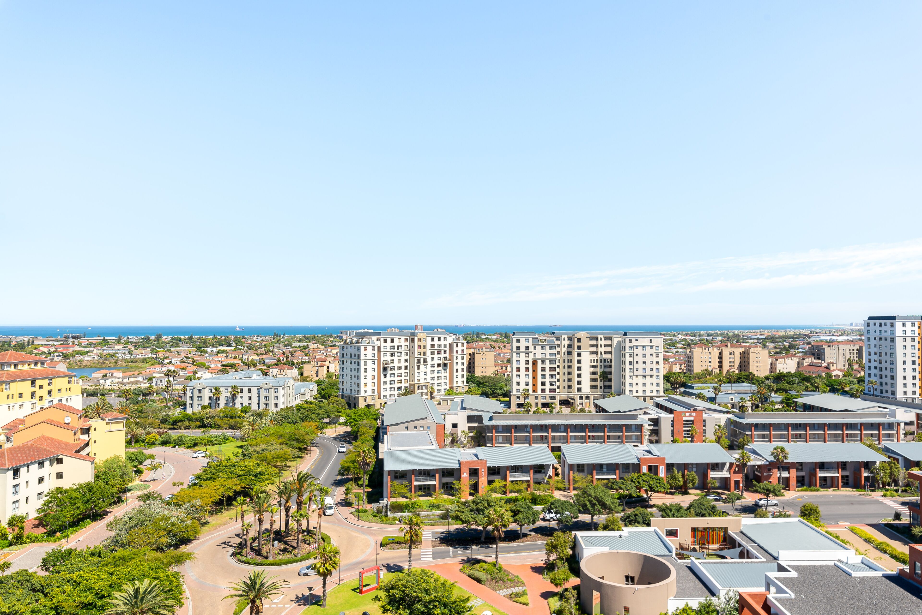 A high-rise hotel complex with multiple buildings, a central courtyard with palm trees, and a view of the ocean.
