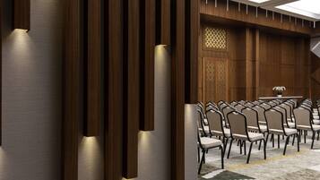 A conference room with a long table and multiple chairs, wooden paneling, and a patterned wall design.