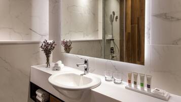 Un baño con lavamanos blanco, espejo y ducha.