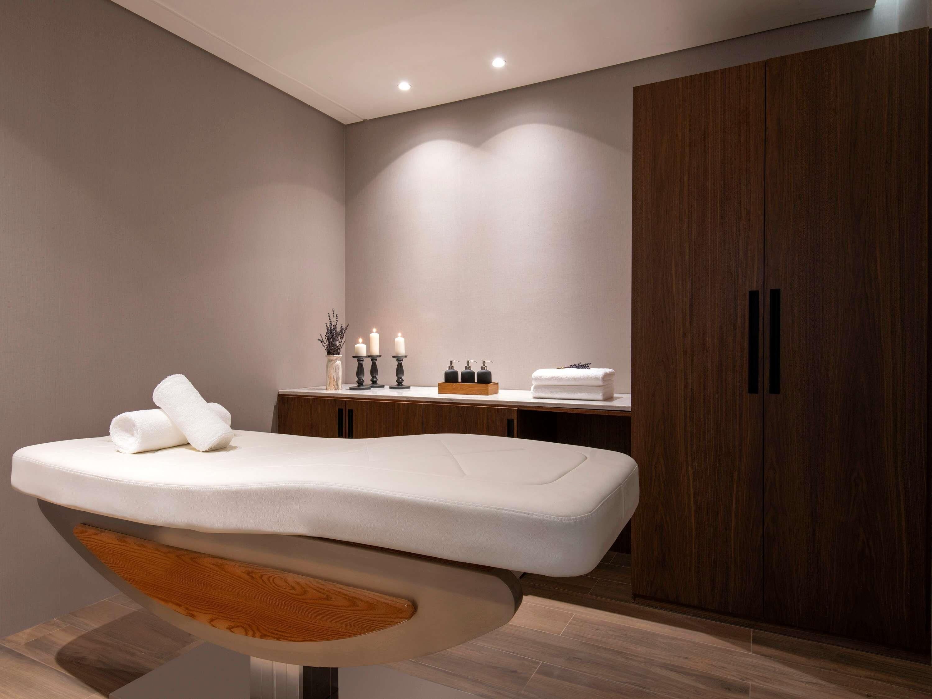 Un baño moderno con una camilla de masaje, armarios de madera y un tocador con velas.