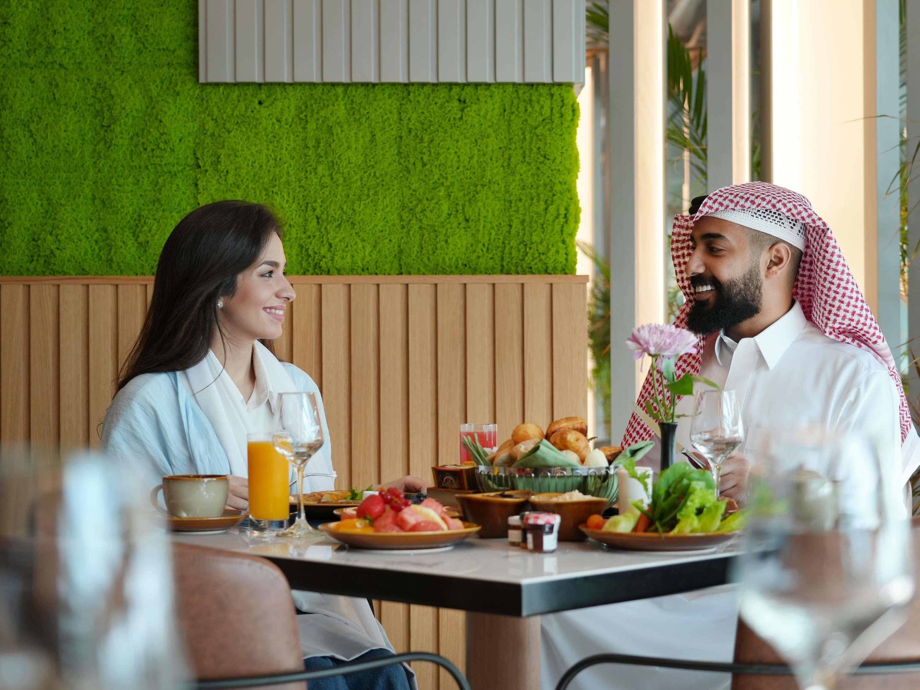 Comedor con pared verde, paneles de madera y una mesa dispuesta con comida y bebidas.