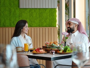 A dining area with a green wall, wooden paneling, and a table set with food and drinks. - Swissotel Living Jeddah (Jeddah)