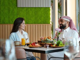 Un espace repas agrémenté d’un mur vert, de lambris en bois et d’une table dressée avec de la nourriture et des boissons.