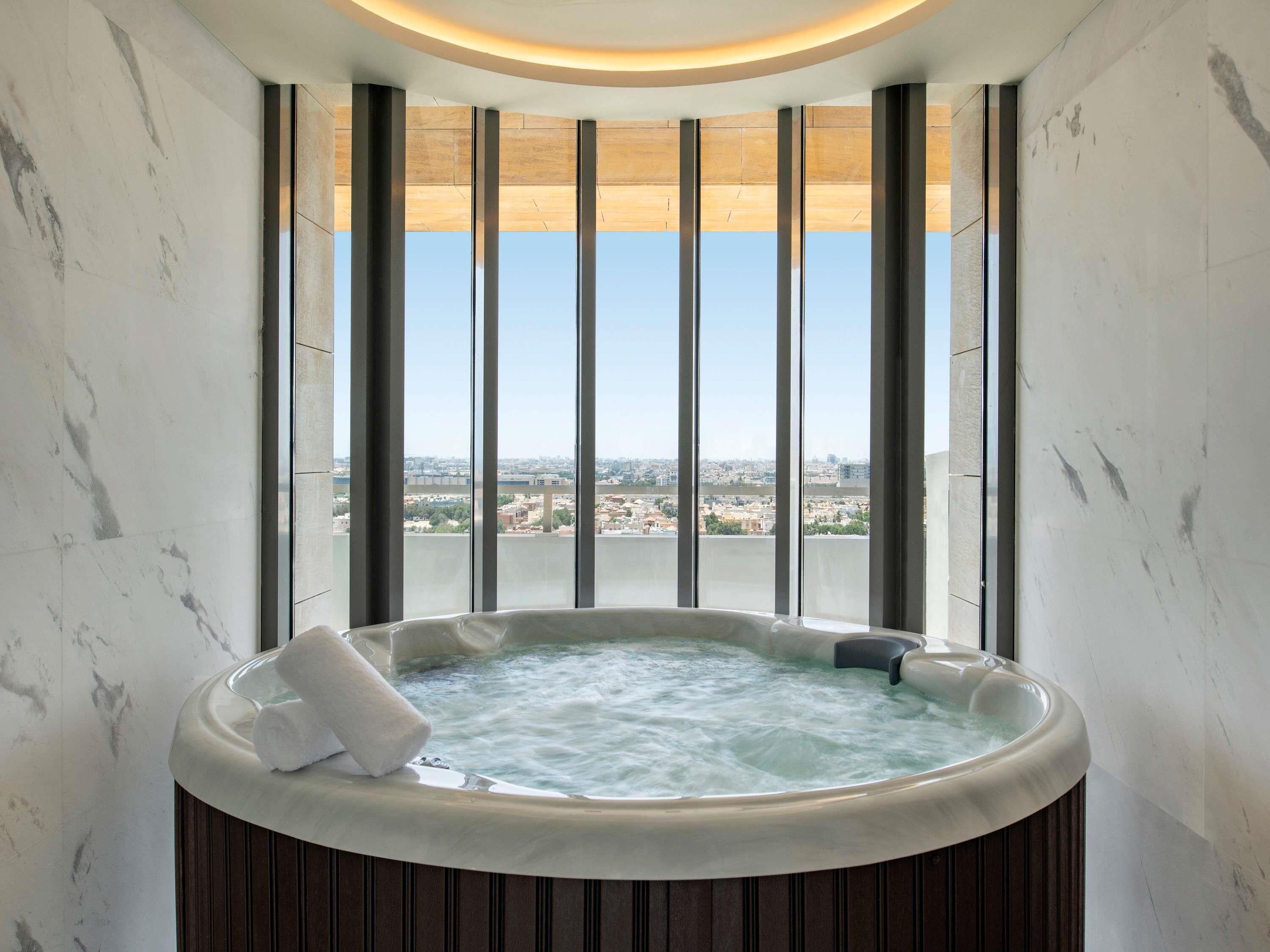 A hot tub with a view of a cityscape through large windows.