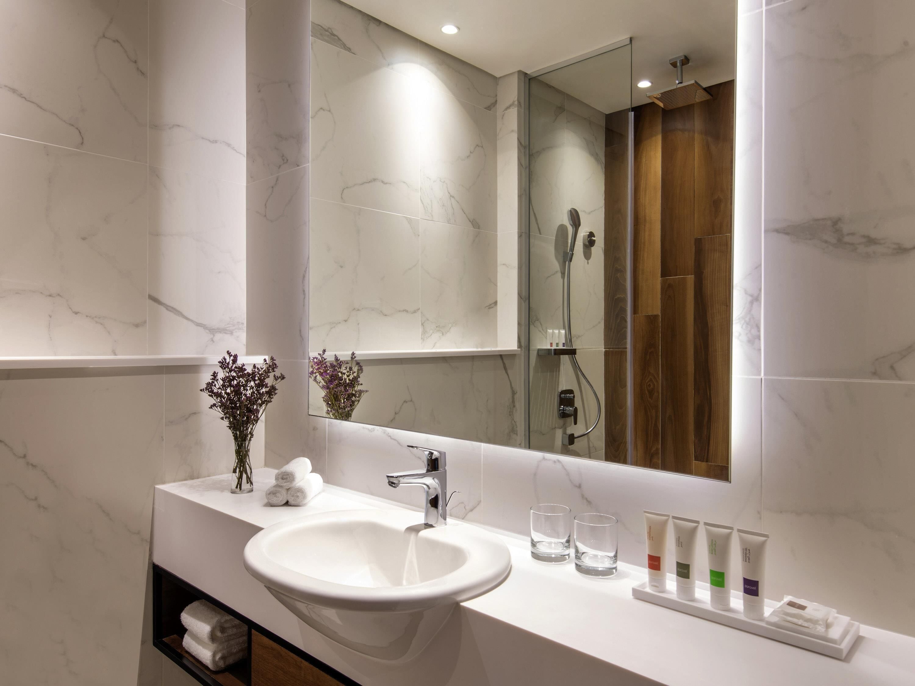 Une salle de bain avec un lavabo blanc, un miroir et une douche.