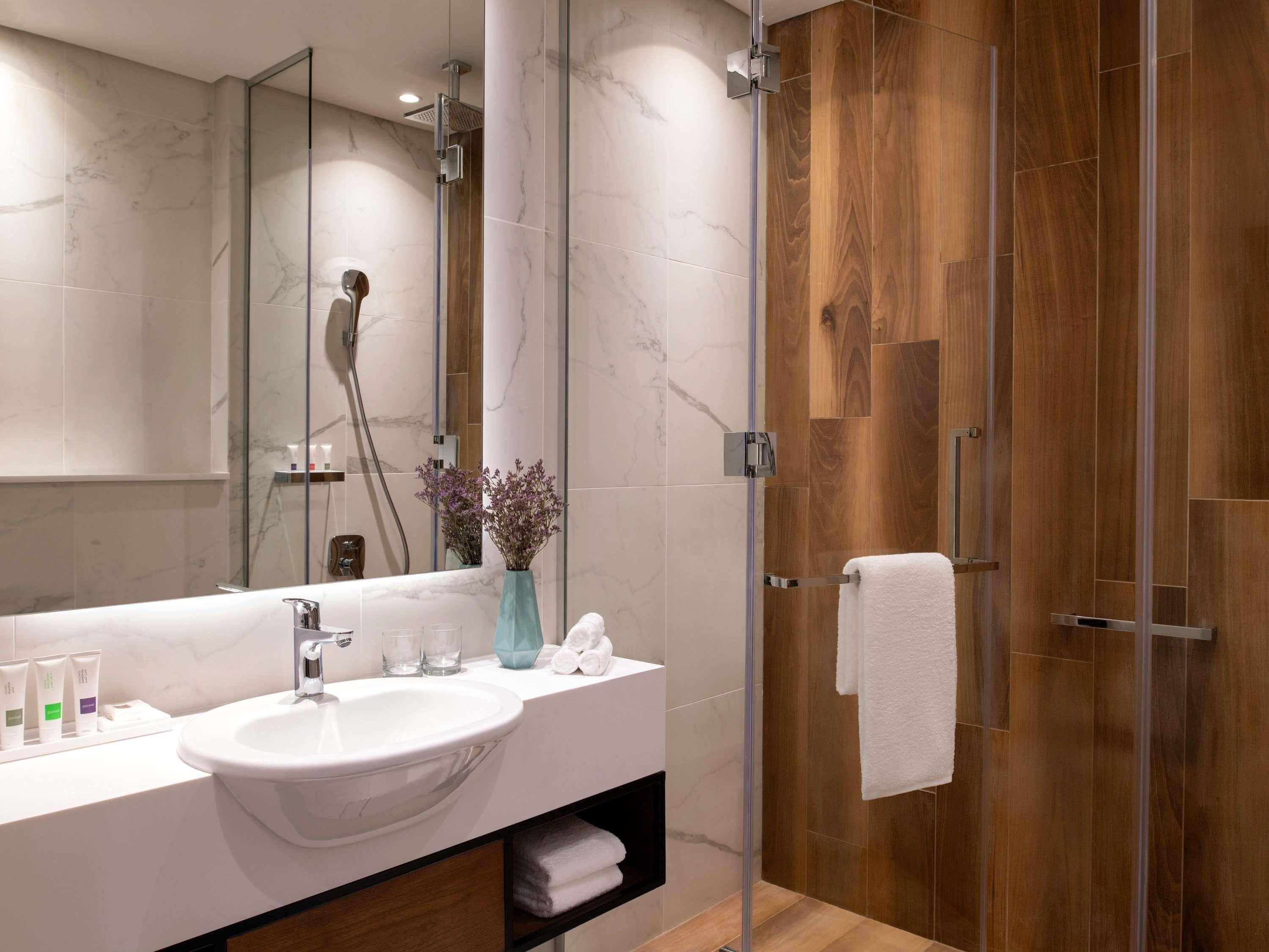 A modern bathroom with a white sink, mirror, and shower.