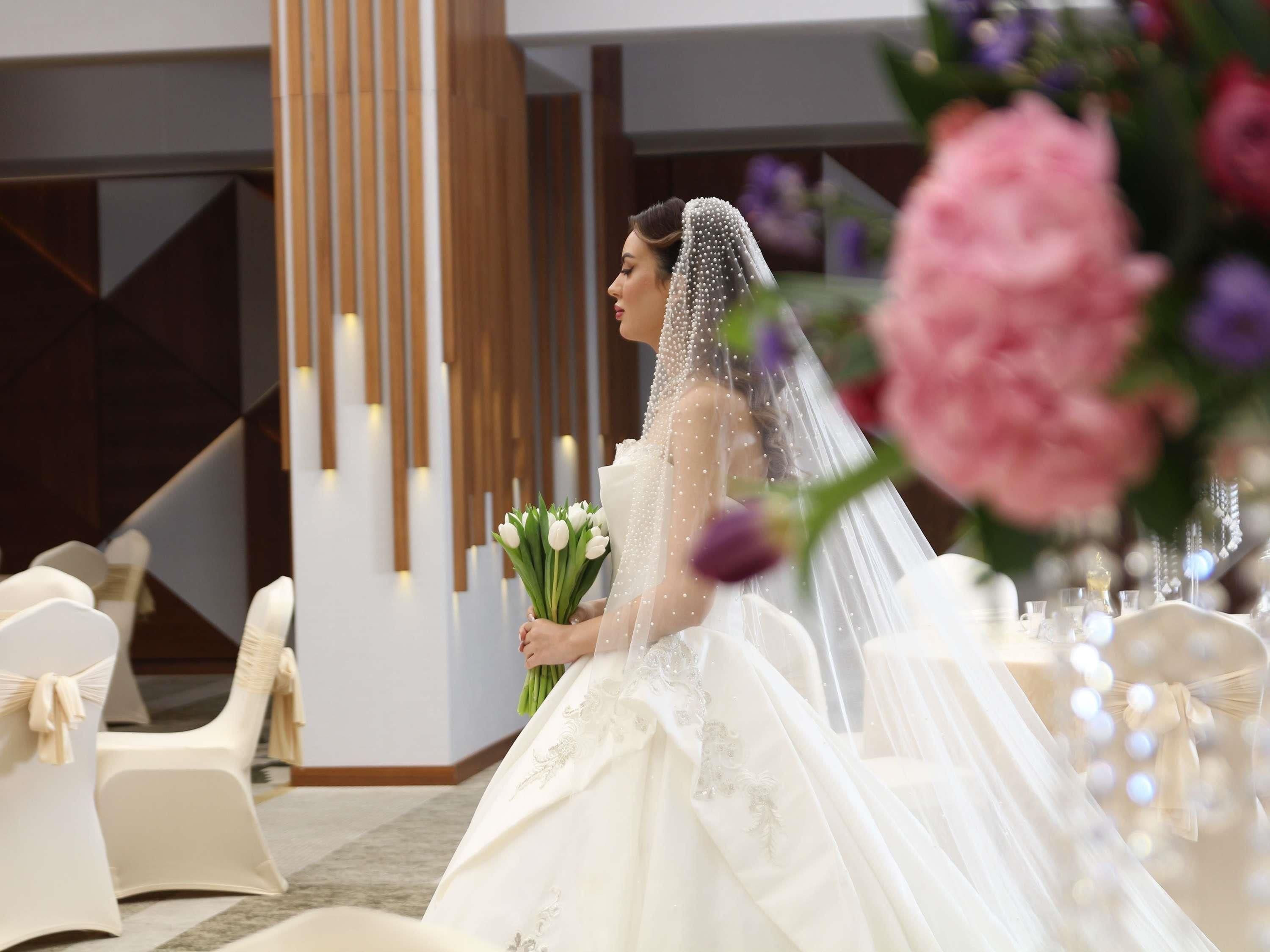 Un salón de bodas con sillas blancas, un pilar de madera y una decoración floral.