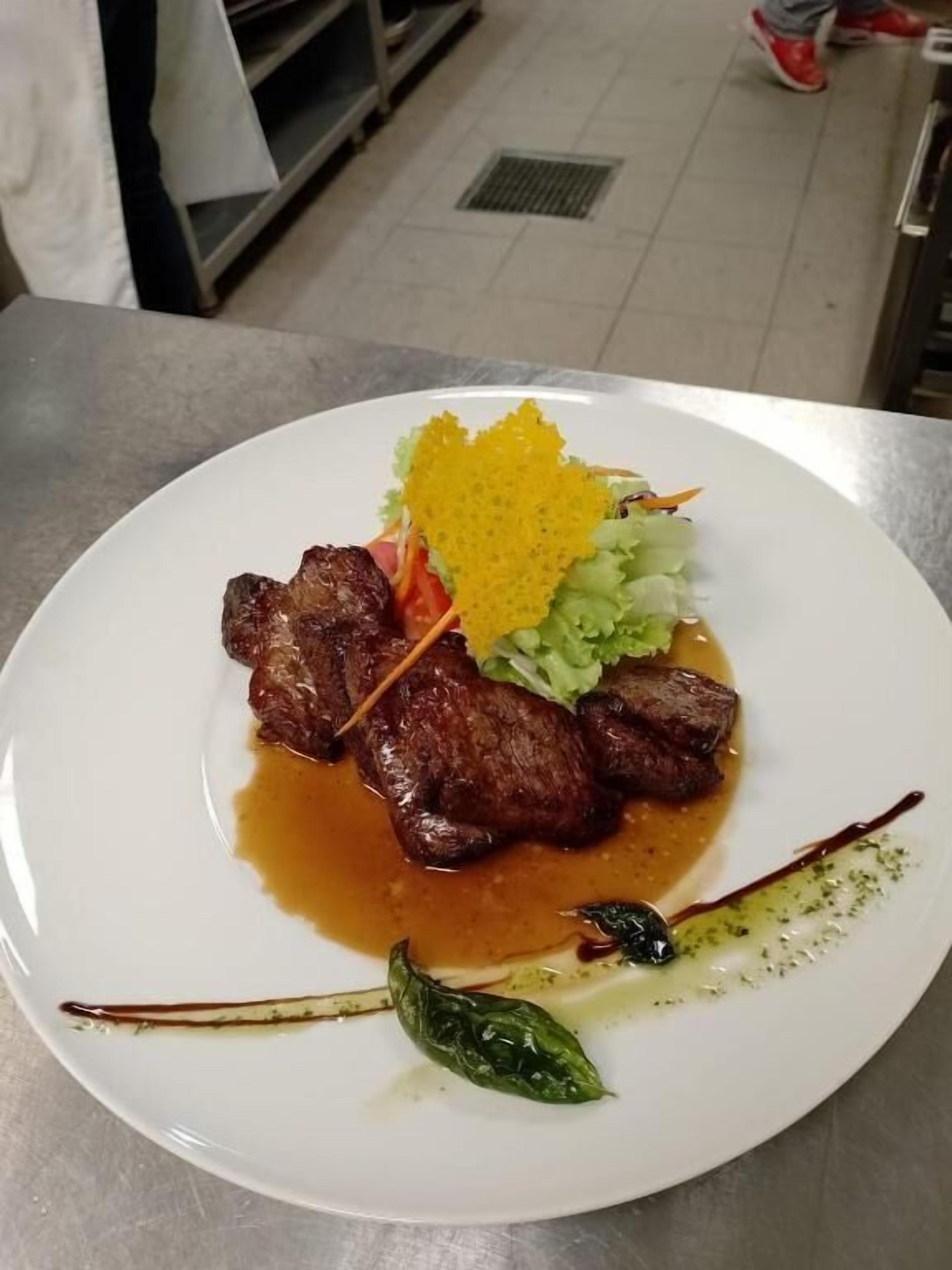 A plate of food with steak, vegetables, and sauce.