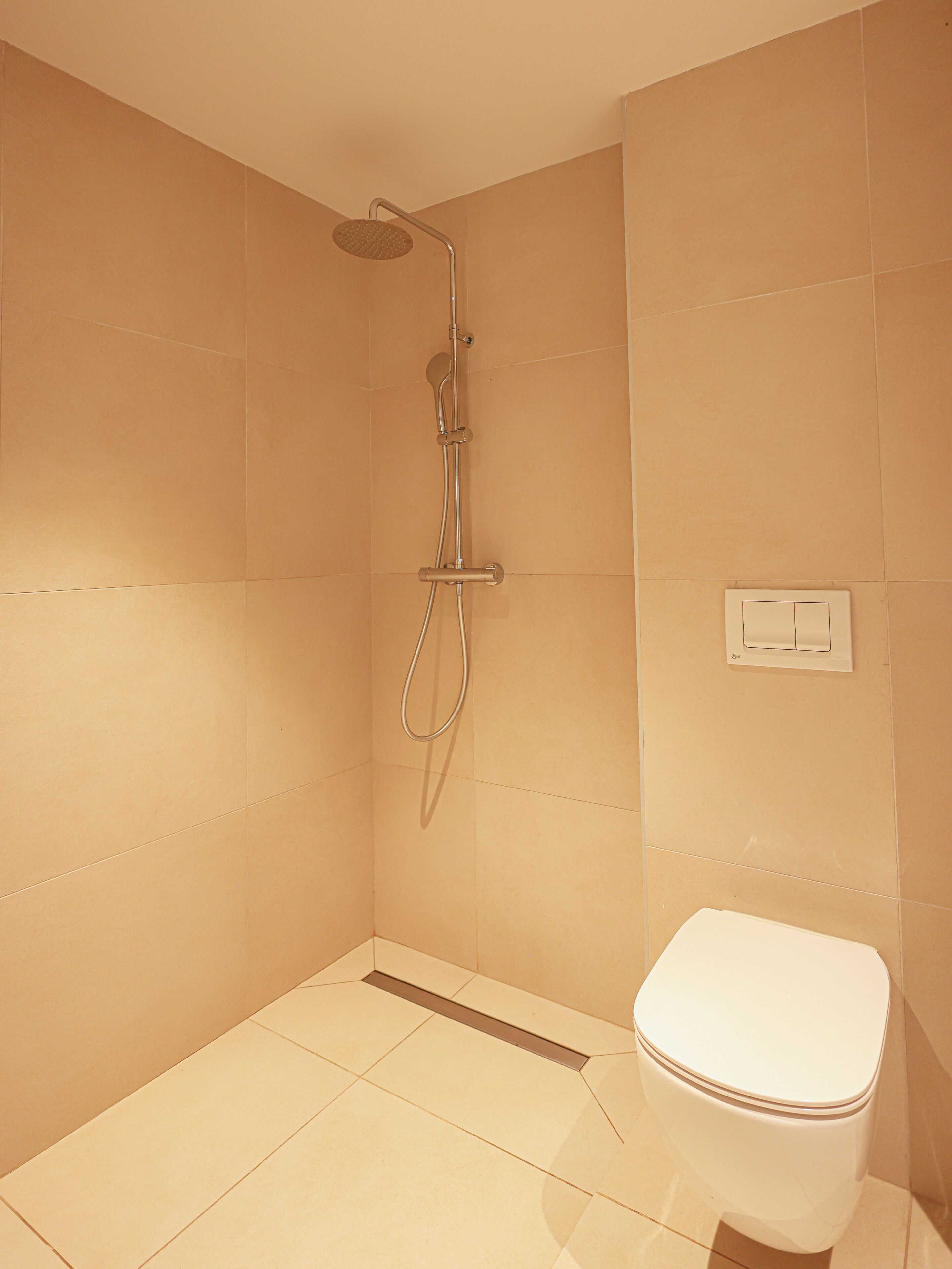 Un baño con ducha, inodoro y panel de control en la pared.