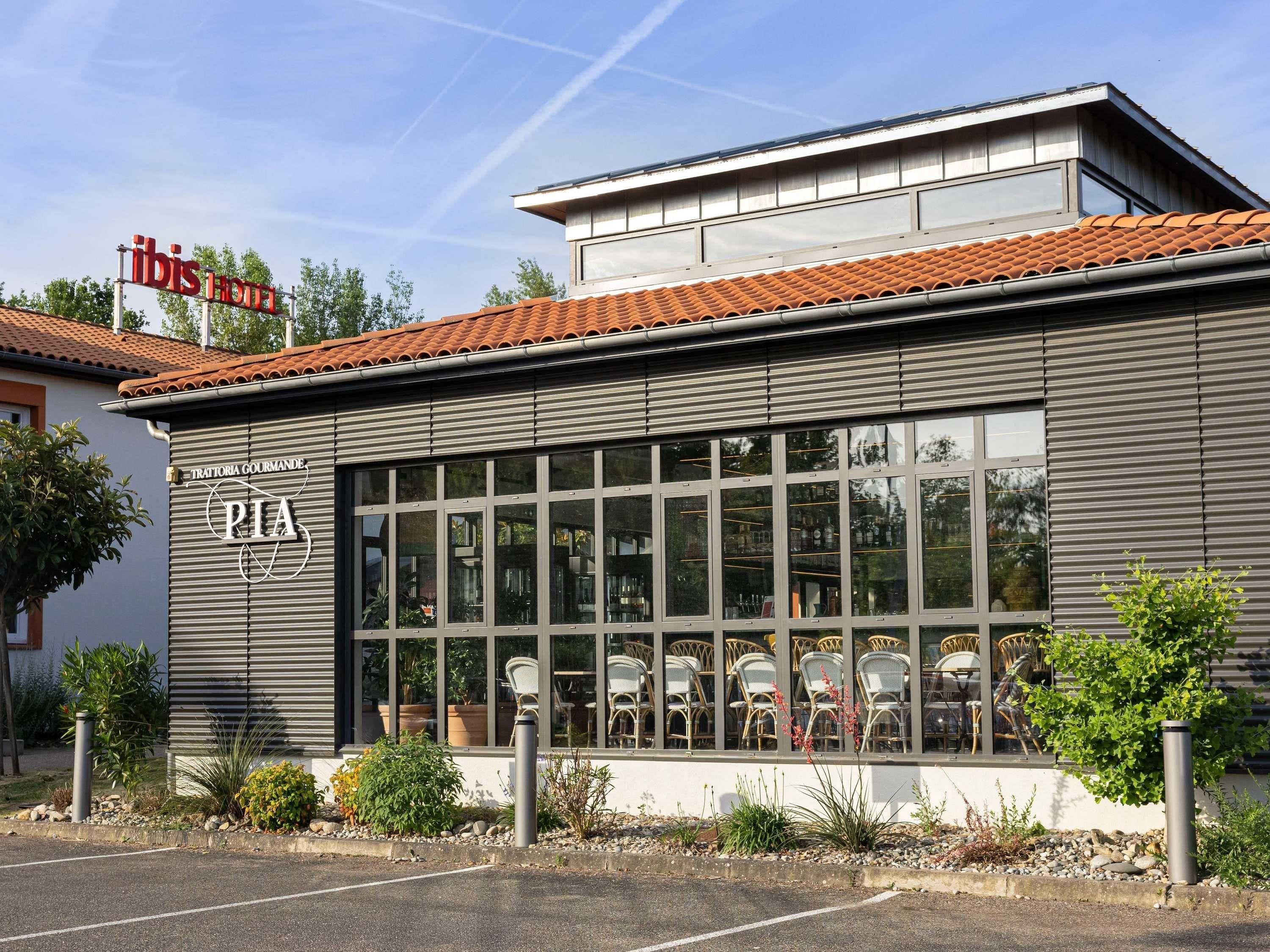 En byggnad med en skylt som visar texten ”Trattoria Gourmande” och ”Pia” på fasaden.