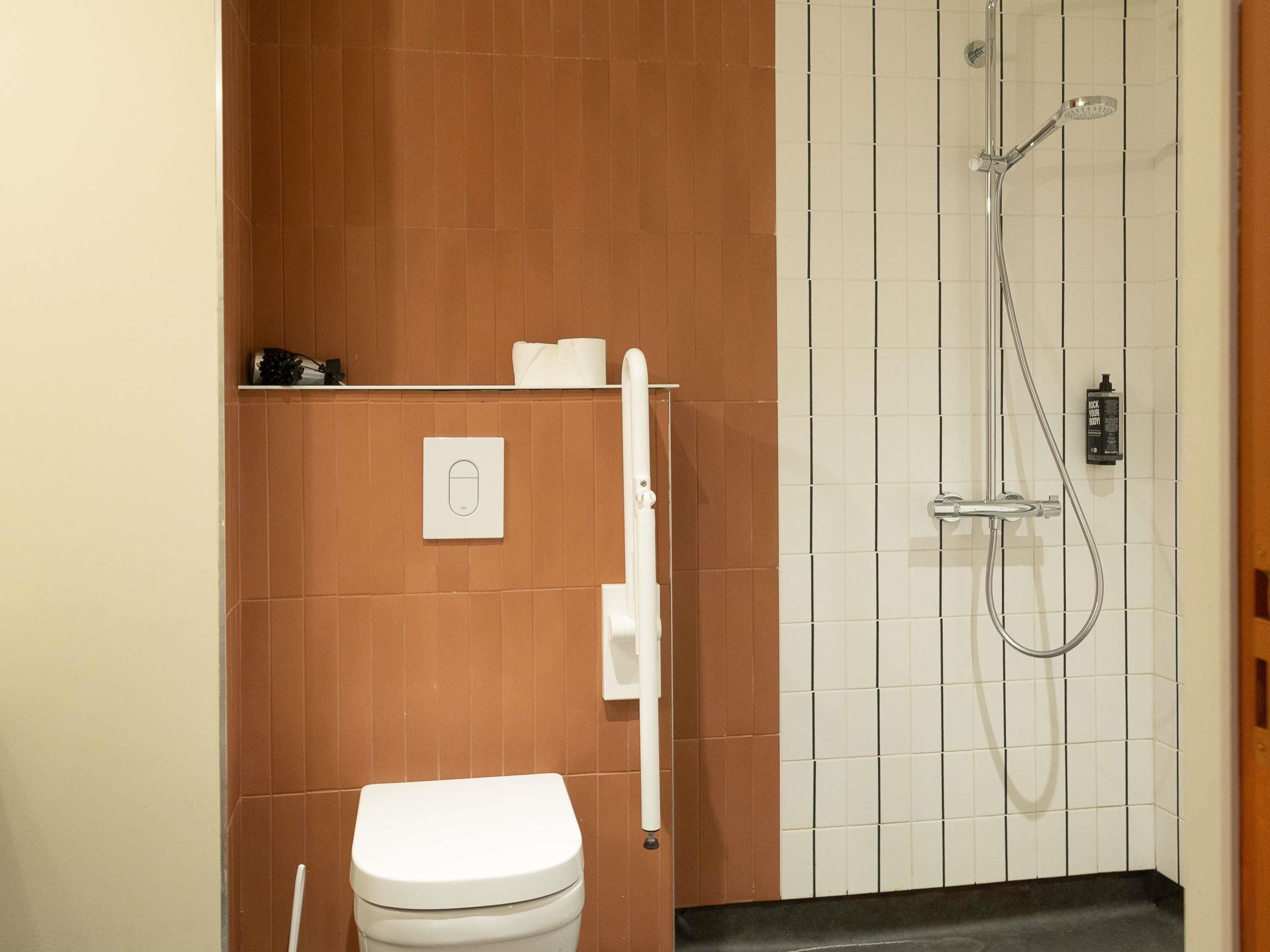 Un baño con inodoro, ducha y toallero.