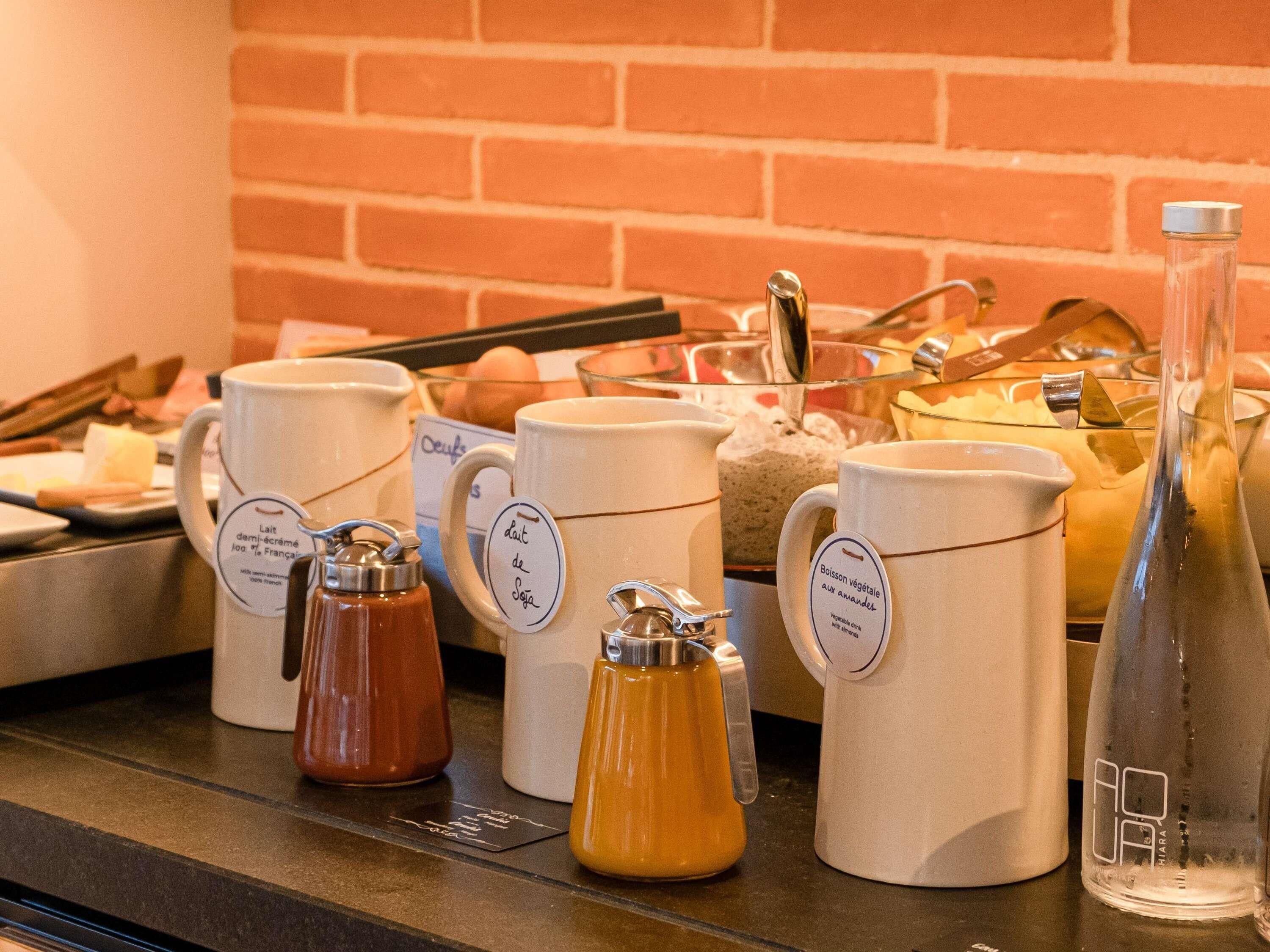 En kaffestation med forskellige krus og en flaske, sandsynligvis til drikkevarer.