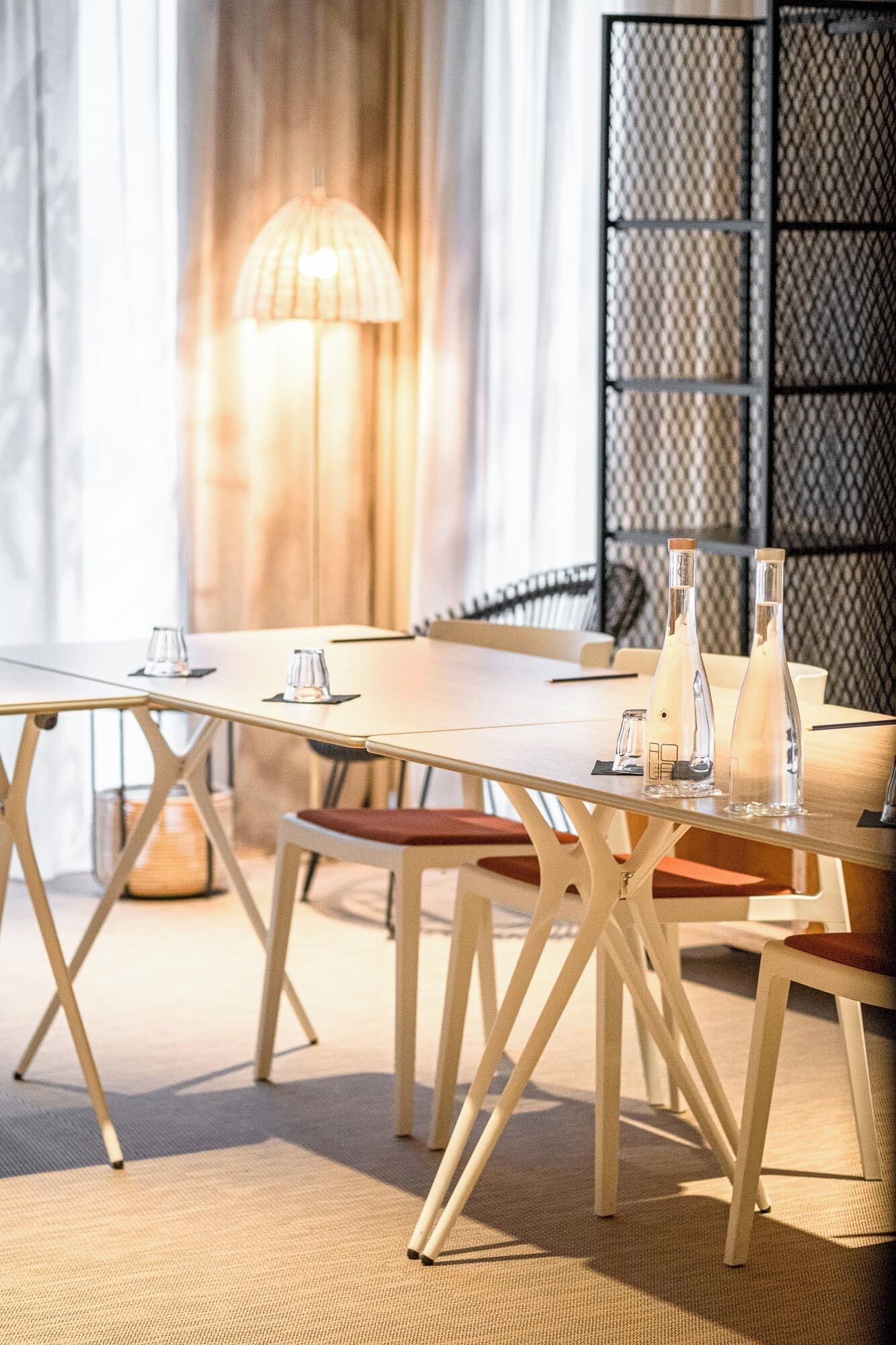 Un espace repas moderne avec une longue table, des chaises et une lampe.
