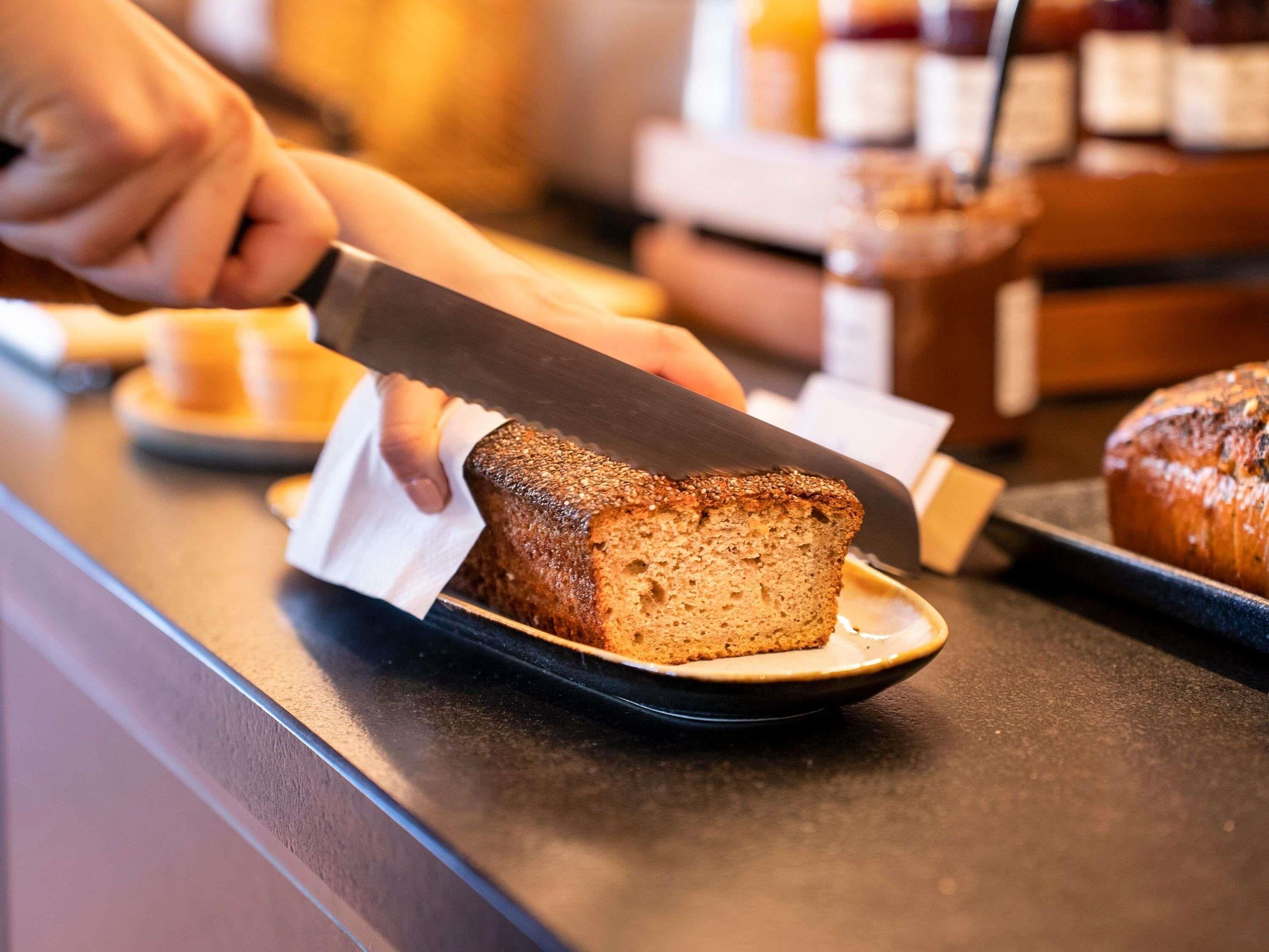 Eine Person schneidet eine Brotlaibe auf einem schwarzen Teller.