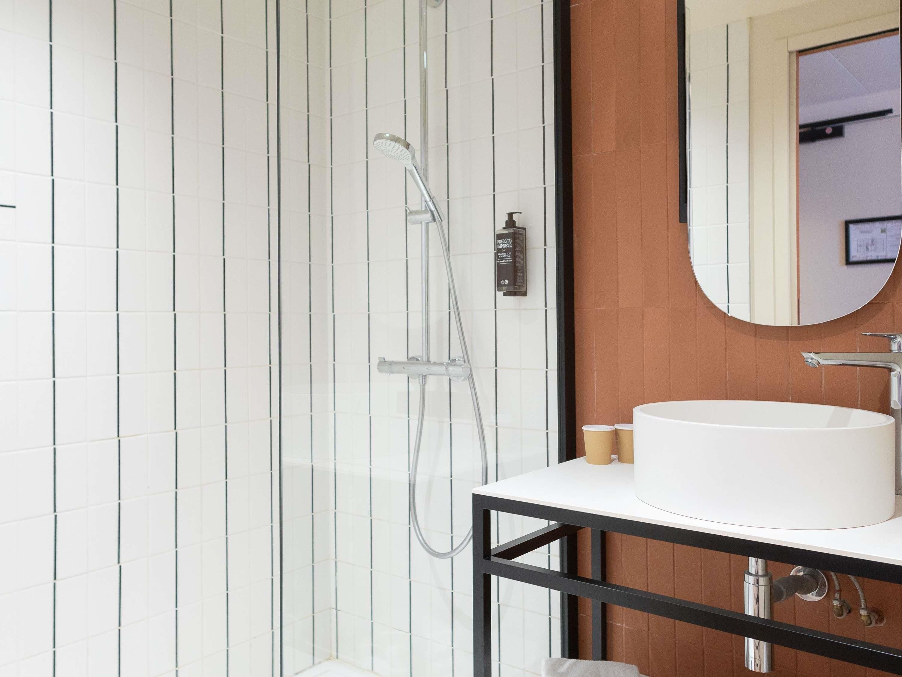 A modern bathroom with a glass-enclosed shower, a white sink, and a mirror above it.
