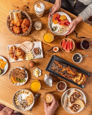 Mesa de madeira com diversos alimentos e bebidas para o café da manhã.