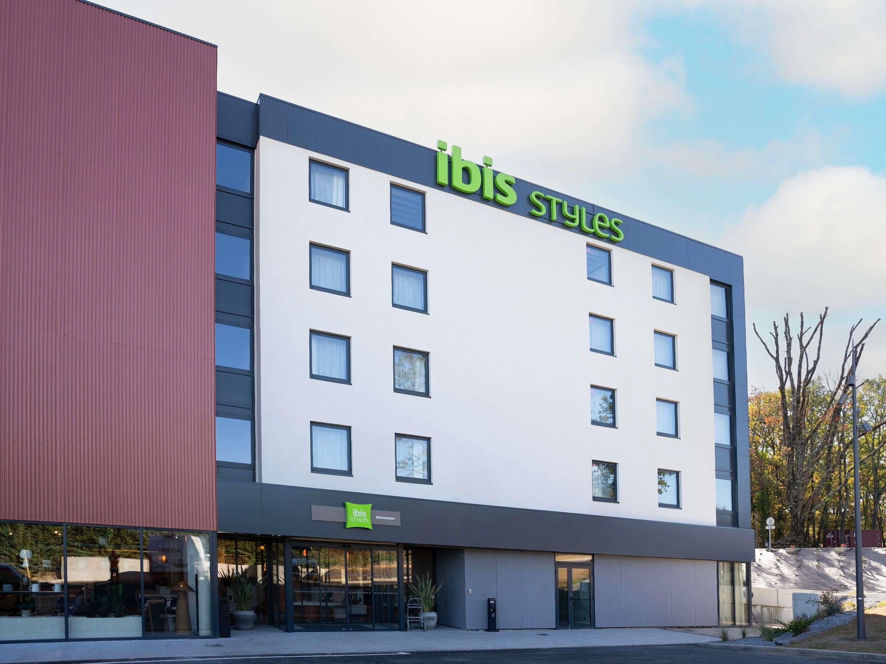 A modern hotel building with a prominent 'ibis Styles' sign, large windows, and a flat roof.