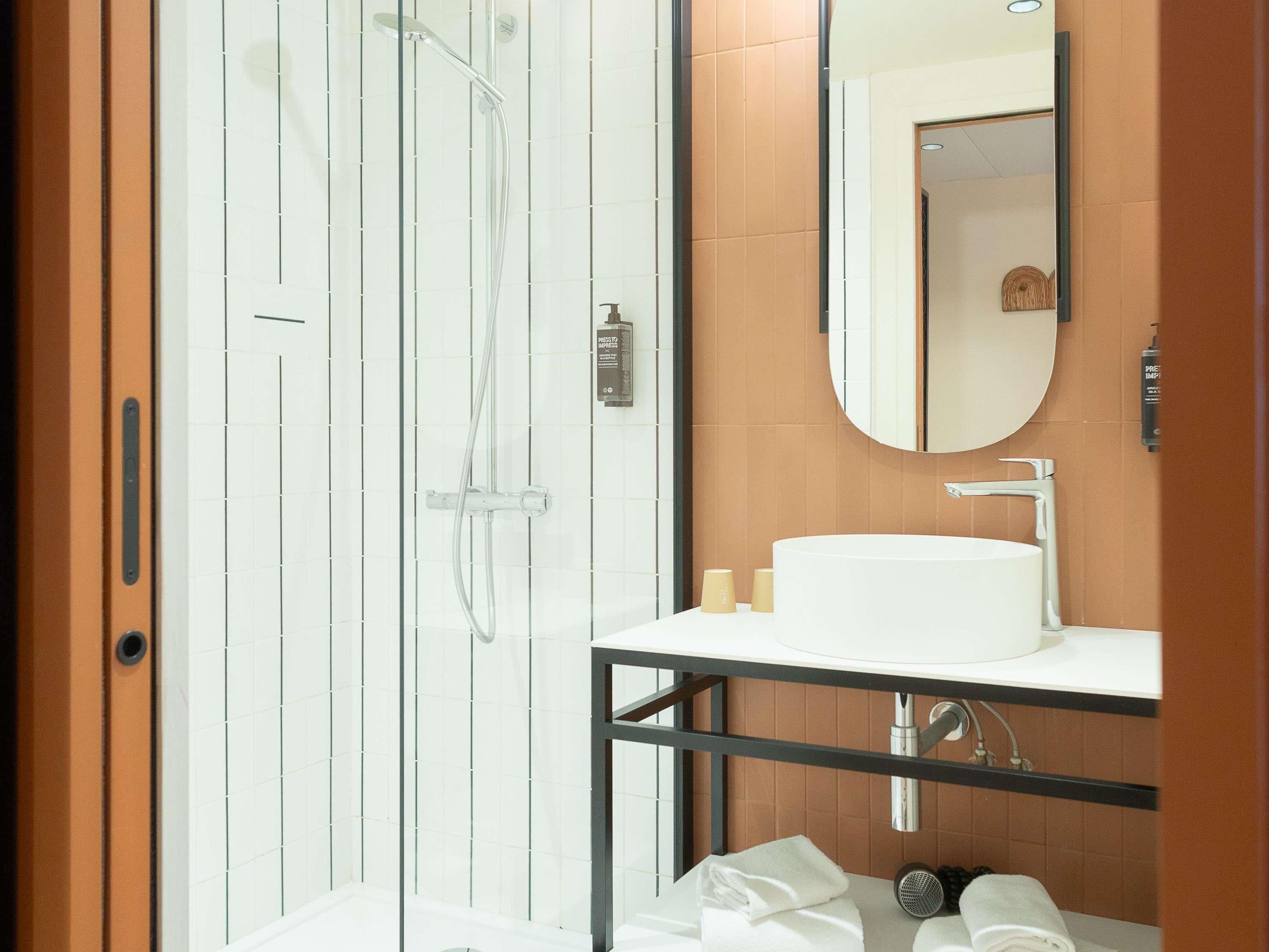 A modern bathroom with a glass-enclosed shower, a white sink, and a mirror above it.