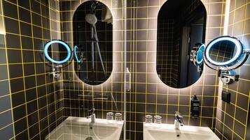 A bathroom with two sinks, a shower, and mirrors with circular frames.