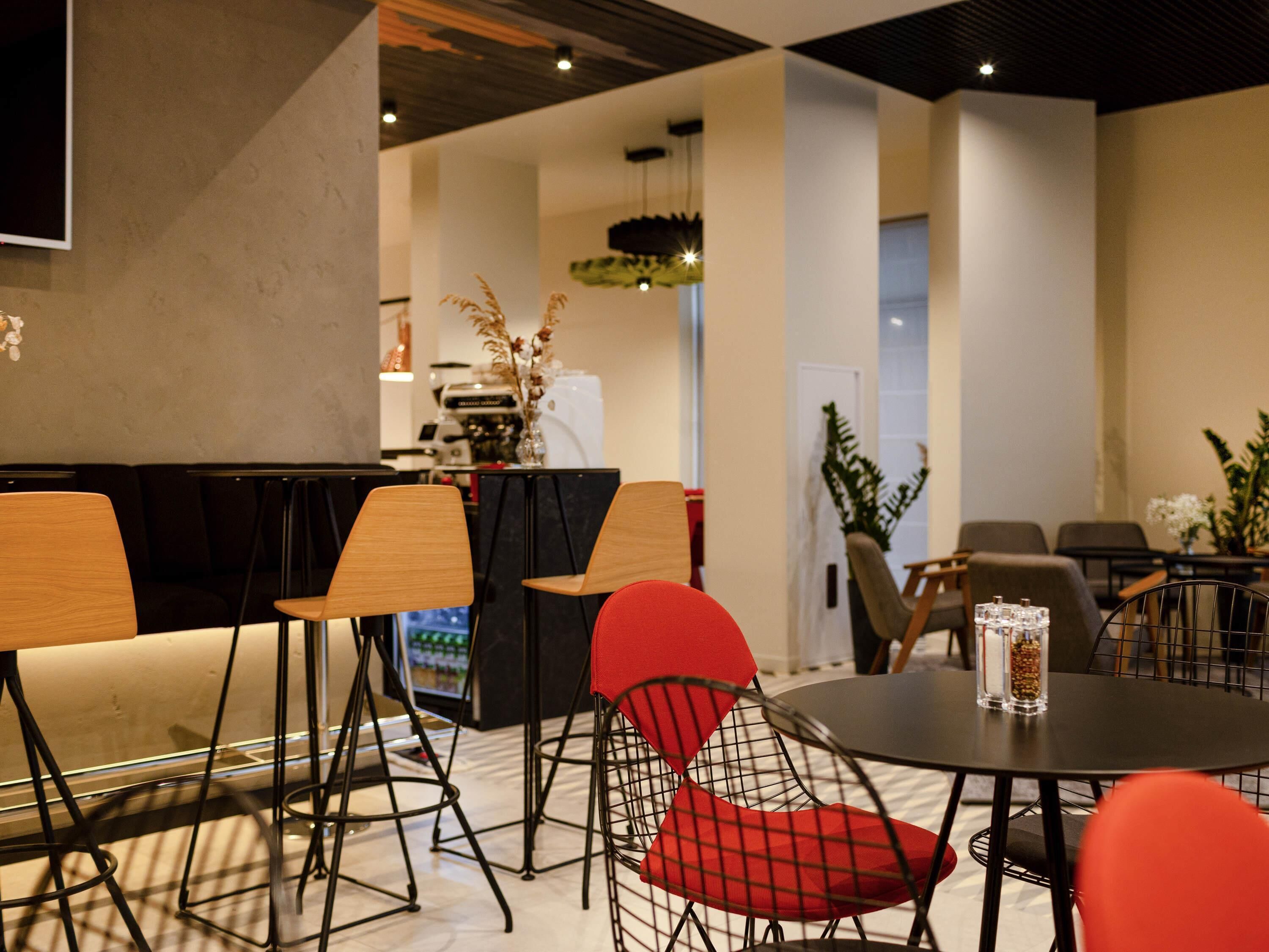 Un interior moderno con arreglos de asientos, una máquina de café y una planta.