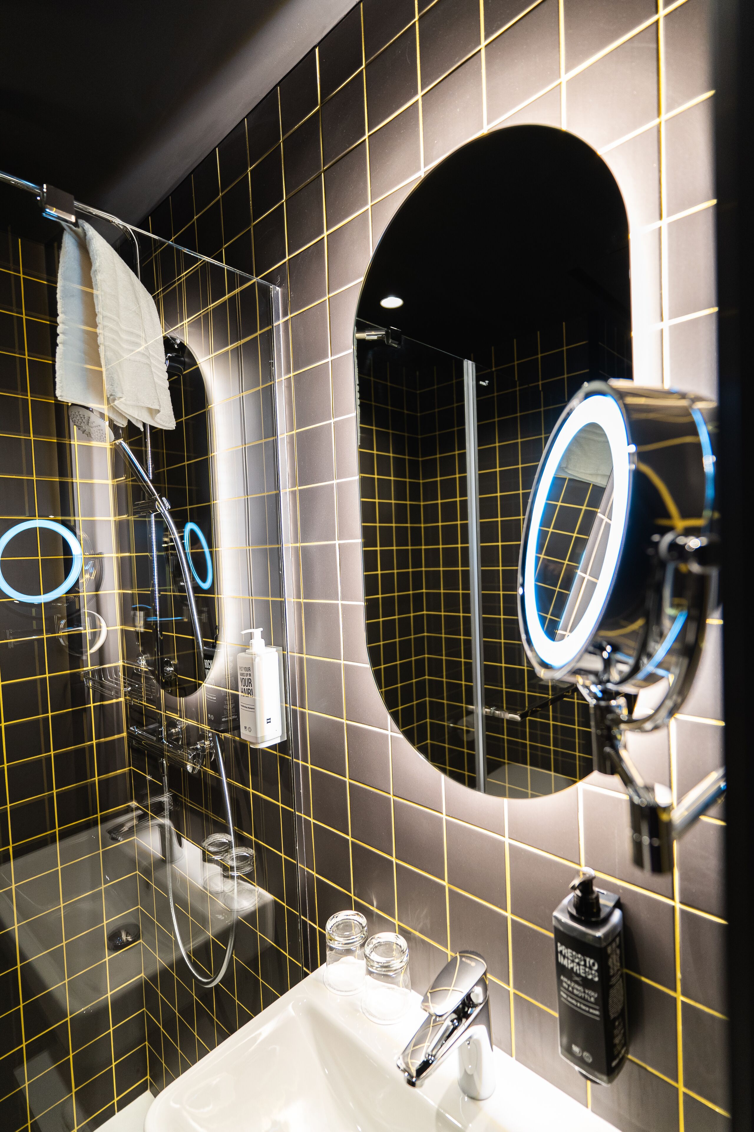 A bathroom with a mirror, sink, and shower.