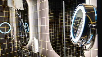A bathroom with a mirror, sink, and shower.