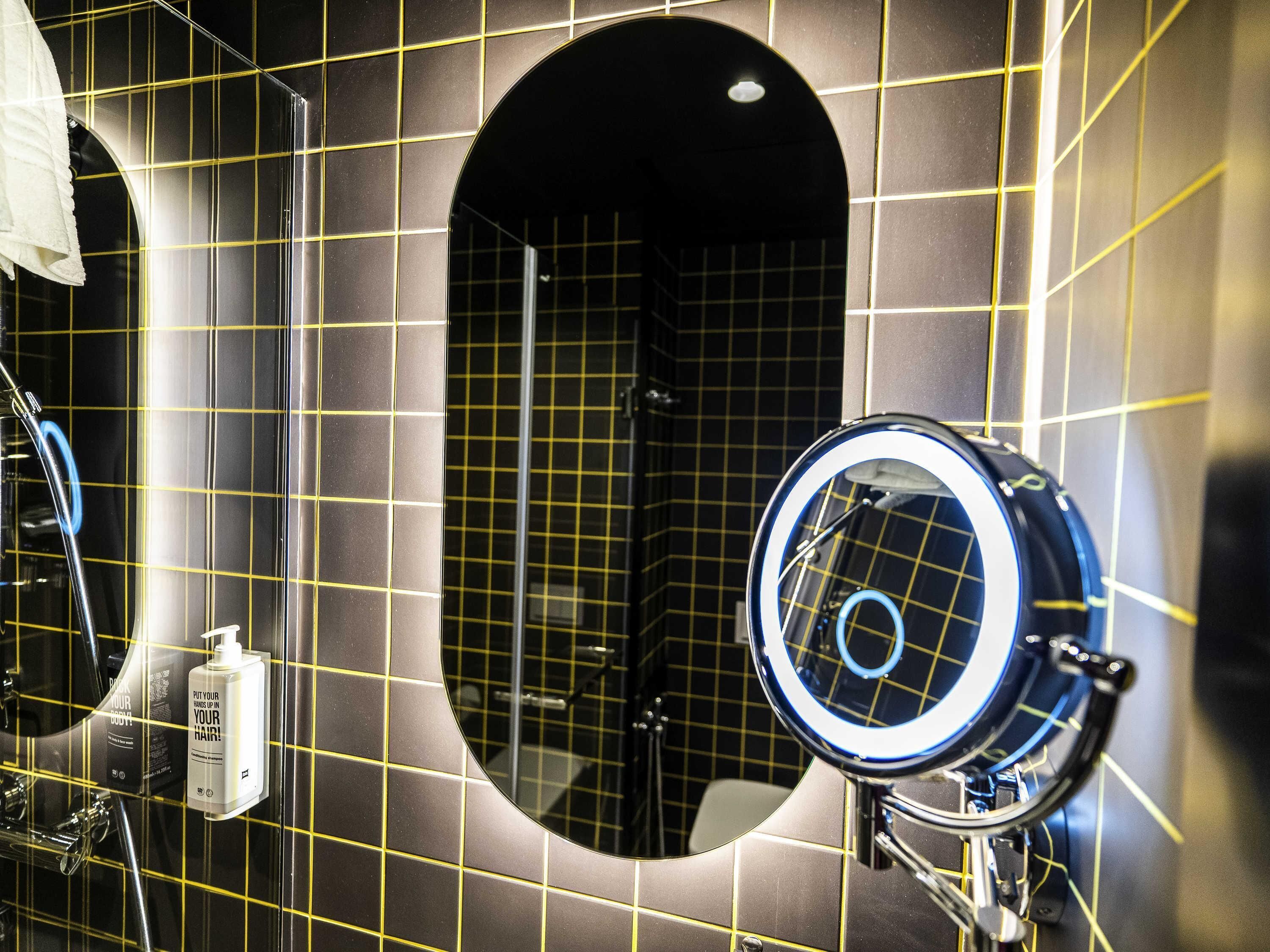 A bathroom with a mirror, a towel dispenser, and a sink.