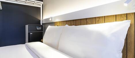 Una habitación de hotel con una cama, una mesita de noche con un teléfono y un equipo de aire acondicionado instalado en la pared.