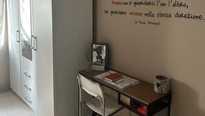 A room with a white wardrobe, a desk with a chair, and a wall with a quote. - Holiday Apartment "Locazione Panta Rei" with A/C & Wi-Fi (Verona)