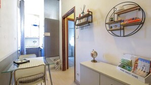 A compact living space with a kitchenette, a dining area, a bookshelf, and a small globe on a console table. - Holiday Apartment "Locazione Panta Rei" with A/C & Wi-Fi (Verona)