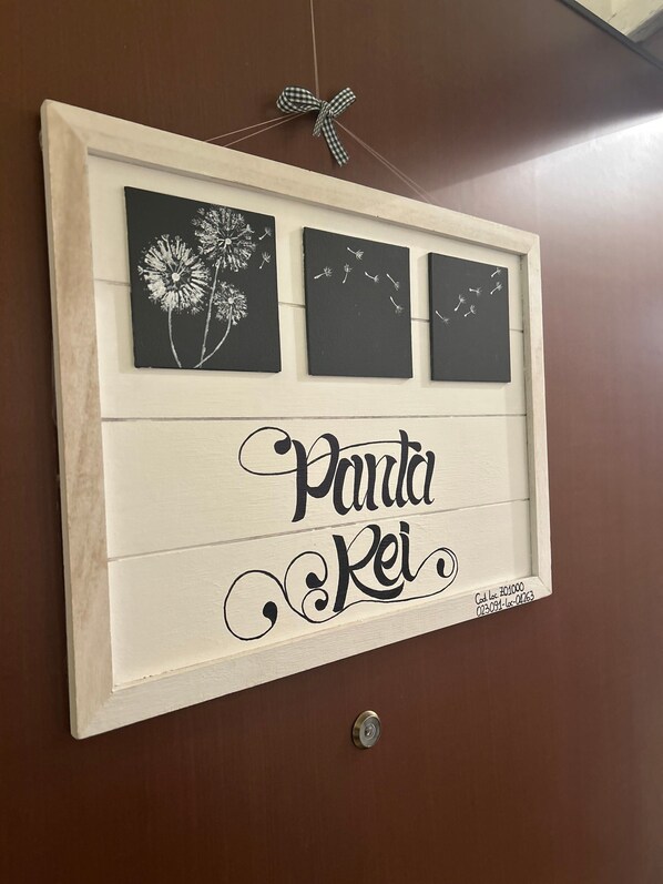 A framed artwork with dandelion illustrations and the text 'Panda Rei' on a wall.