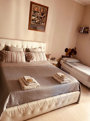 A neatly made bed with a quilted headboard, a bedside table with a lamp, and a framed picture above the bed.