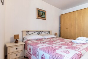 Une chambre à coucher comprenant un lit, une table de chevet, une lampe et une armoire en bois.