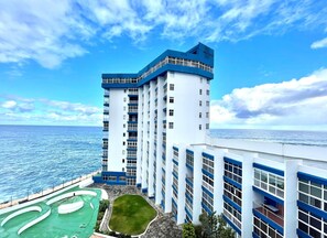 Een hoog hotel met zwembad en uitzicht op de oceaan.
