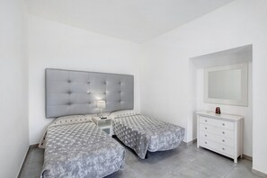 A bedroom with two beds, a nightstand, a dresser, and a mirror.