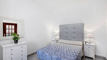 Ein Schlafzimmer mit Bett, Nachttischen, einem Schminktisch und einem Blumentopf.