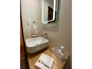 A bathroom with a white sink, a mirror, a towel, and a bottle of hand soap.