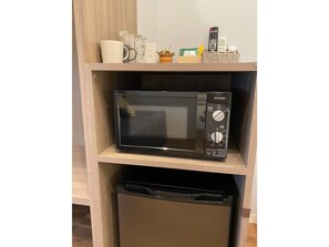 A microwave on a shelf with a dishwasher below it.