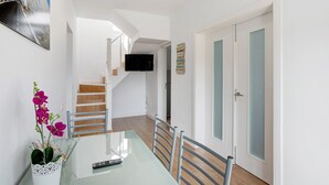A dining area with a glass table, chairs, a remote control, and a potted orchid. - Vacation Home 'Casa Micaela 2' with Sea View, Terrace, Balcony & Wi-Fi (El Sauzal)