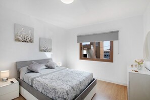 A bedroom with a bed, bedside tables, a window with a view, and artwork on the wall.