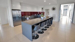 Una cocina moderna con una isla central, electrodomésticos de acero inoxidable y taburetes de bar.
