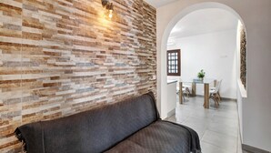 Ein modernes Interieur mit einer gemusterten Ziegelwand, einem dunklen Sofa und einem Essbereich mit Tisch und Stühlen.