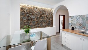Eine moderne Küche mit Steinwand, weißen Schränken und einer gefliesten Spritzschutzwand.